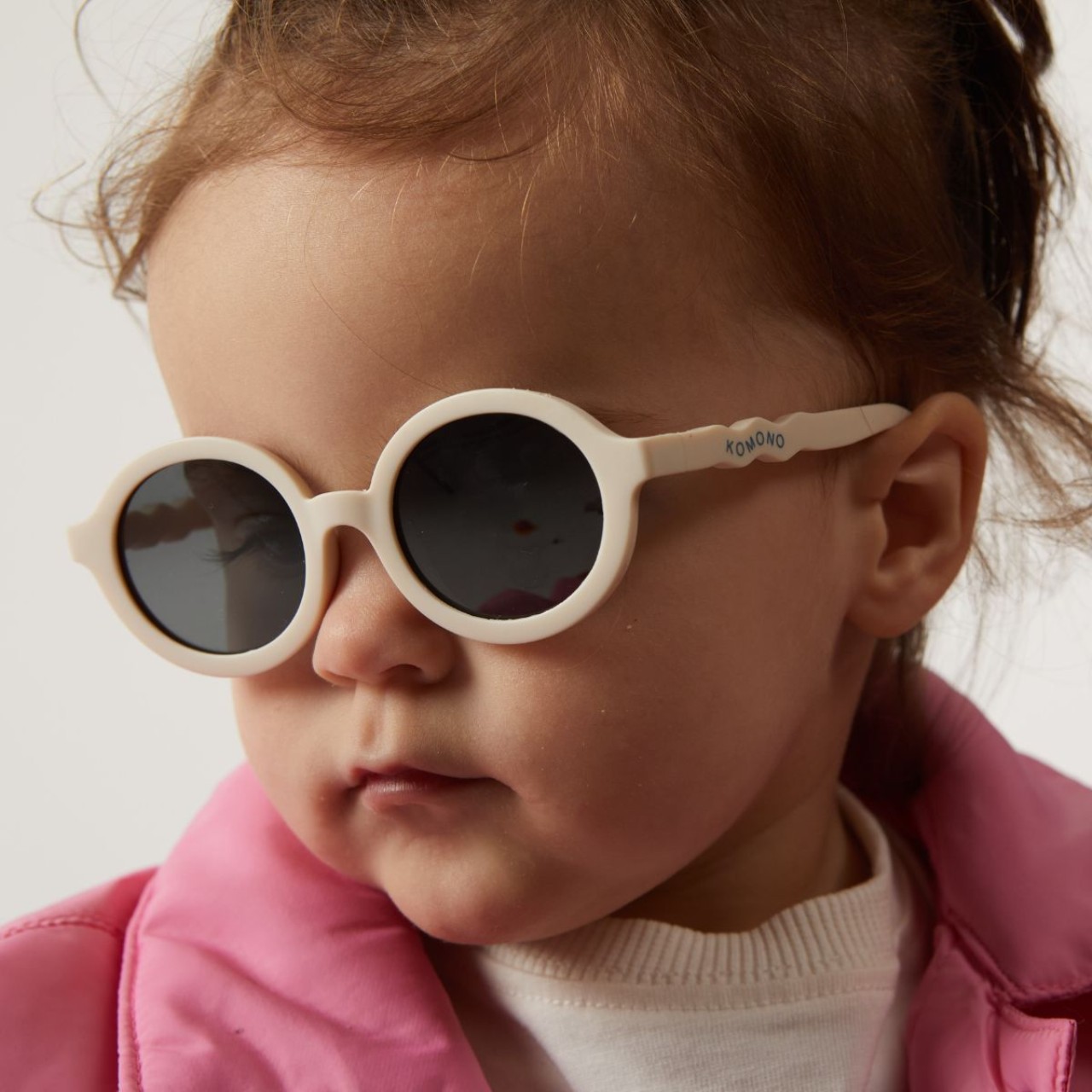 Kinder-Sonnenbrille, runde Brille, weißes Gestell, dunkle Gläser, pink Jacke